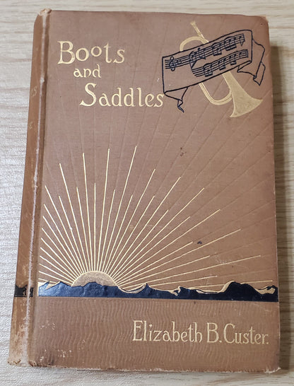 Custer, Elizabeth. Boots and Saddles. NY: Harper &amp; Bros, 1885. 1st ed, 1st issue without a frontis or map. Pict cloth, gilt. Spine lean. Fraying, Cloth frayed. Bottom ½” spine soiled. Good